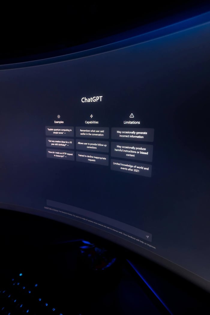 Close-up of ChatGPT's interface displayed on a curved monitor in a dimly lit environment.